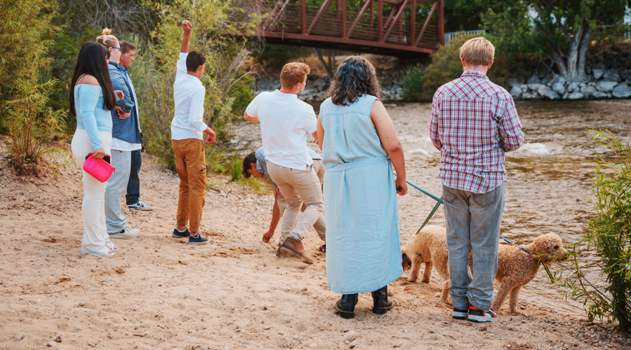 Members of Vineyard family with clients at the river's edge all standing on sandy shoreline